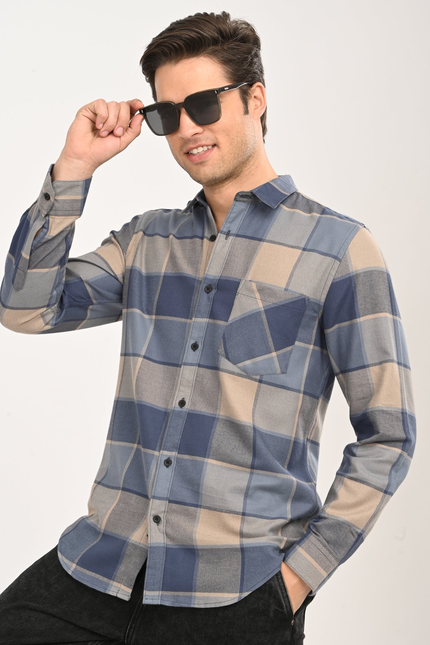Front view of a model wearing a slate blue, navy, and beige large-block checkered casual shirt with black jeans.