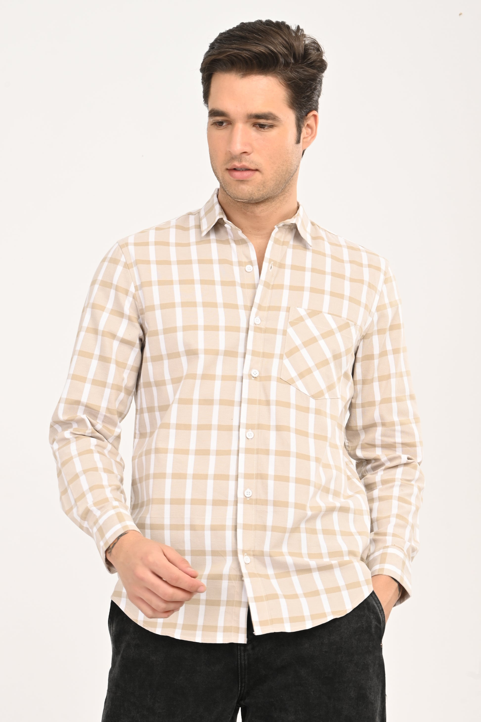 Model wearing a sand beige and white windowpane plaid casual shirt with black jeans.